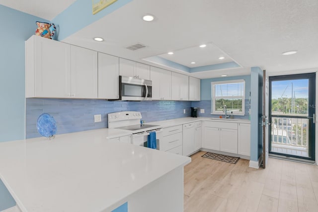 18650 Gulf Blvd Unit 203, Indian Shores, FL 33785 - kitchen featuring stainless steel microwave, electric stove, a sink, light countertops, and a peninsula