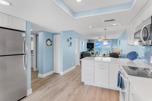 18650 Gulf Blvd Unit 203, Indian Shores, FL 33785 - kitchen featuring appliances with stainless steel finishes, a peninsula, white cabinetry, light wood-style floors, and open floor plan