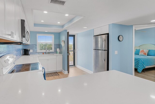 18650 Gulf Blvd Unit 203, Indian Shores, FL 33785 - kitchen with stainless steel appliances, a sink, light wood finished floors, light countertops, and backsplash