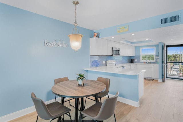 18650 Gulf Blvd Unit 203, Indian Shores, FL 33785 - kitchen with electric stove, stainless steel microwave, light wood-style floors, white cabinetry, and a peninsula