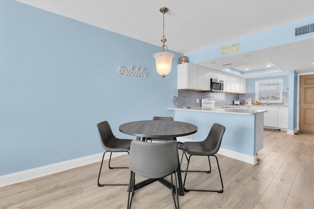18650 Gulf Blvd Unit 203, Indian Shores, FL 33785 - dining area featuring light wood-style floors, a tray ceiling, and recessed lighting