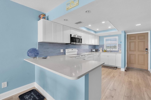 18650 Gulf Blvd Unit 203, Indian Shores, FL 33785 - kitchen featuring white electric stove, stainless steel microwave, a peninsula, tasteful backsplash, and light countertops