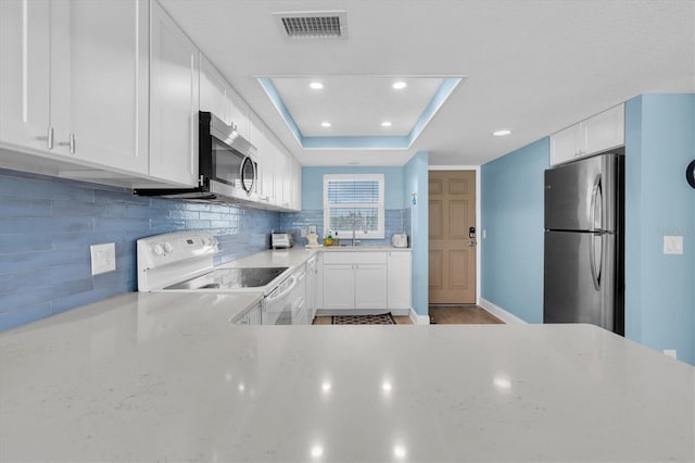 18650 Gulf Blvd Unit 203, Indian Shores, FL 33785 - kitchen featuring appliances with stainless steel finishes, backsplash, white cabinetry, recessed lighting, and a raised ceiling