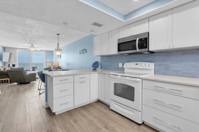 18650 Gulf Blvd Unit 203, Indian Shores, FL 33785 - kitchen with white range with electric stovetop, stainless steel microwave, a peninsula, light countertops, and a wall of windows