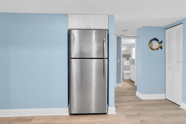 18650 Gulf Blvd Unit 203, Indian Shores, FL 33785 - kitchen with freestanding refrigerator, light wood finished floors, white cabinetry, and a textured ceiling