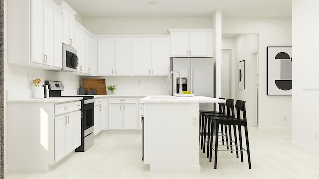 kitchen featuring stainless steel appliances, a breakfast bar area, a center island with sink, light countertops, and white cabinets