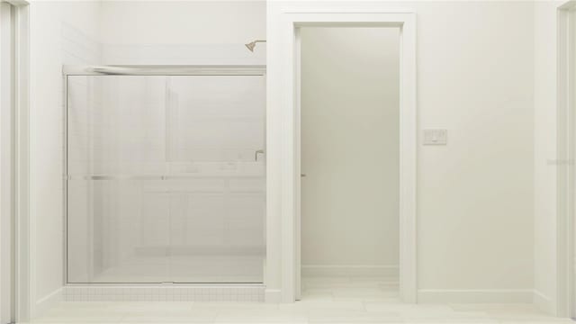 bathroom with baseboards and a stall shower