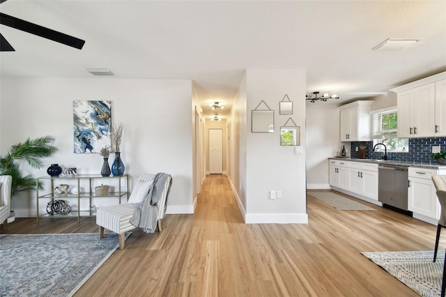 kitchen with dishwasher, light wood finished floors, decorative backsplash, and white cabinets