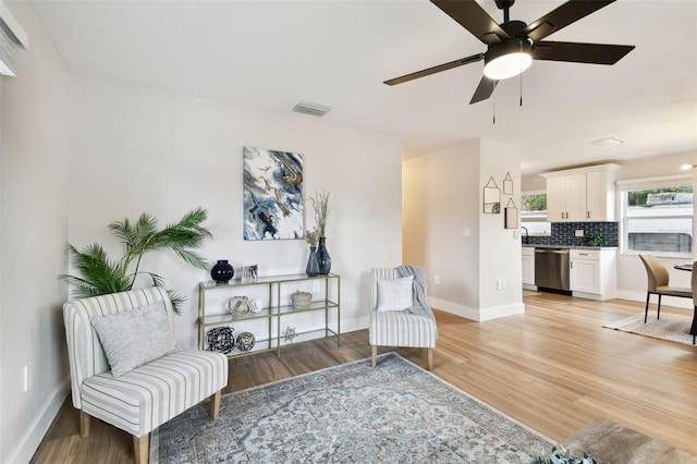 sitting room with a ceiling fan, baseboards, and light wood-style flooring