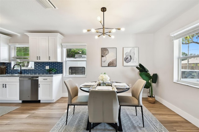 dining area with healthy amount of natural light, a chandelier, baseboards, and light wood finished floors