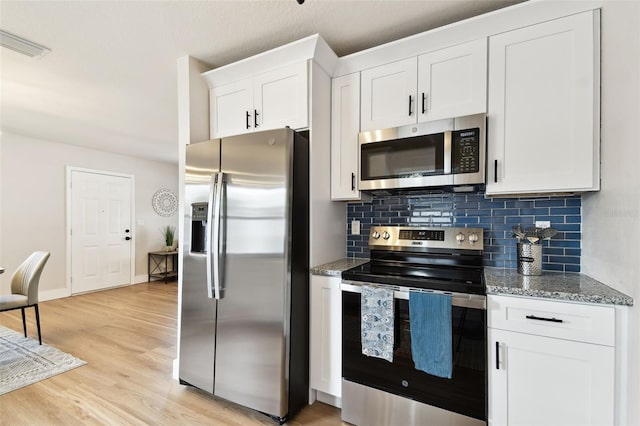 kitchen with appliances with stainless steel finishes, backsplash, stone countertops, white cabinetry, and light wood finished floors