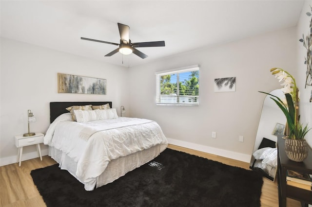 bedroom featuring light wood-type flooring, a ceiling fan, and baseboards