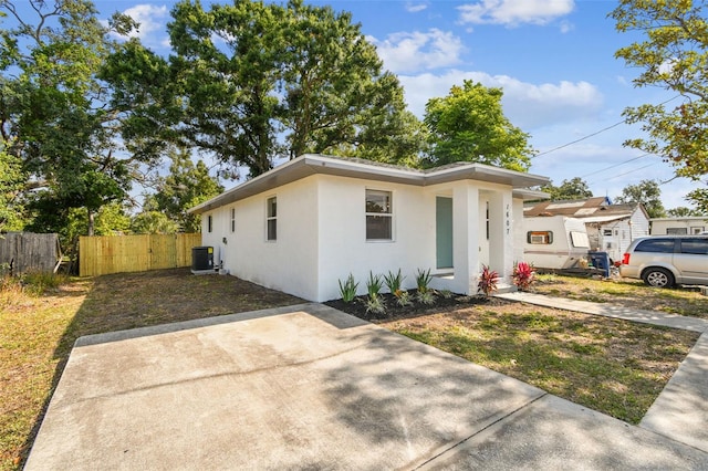 single story home featuring stucco siding, fence, and central AC