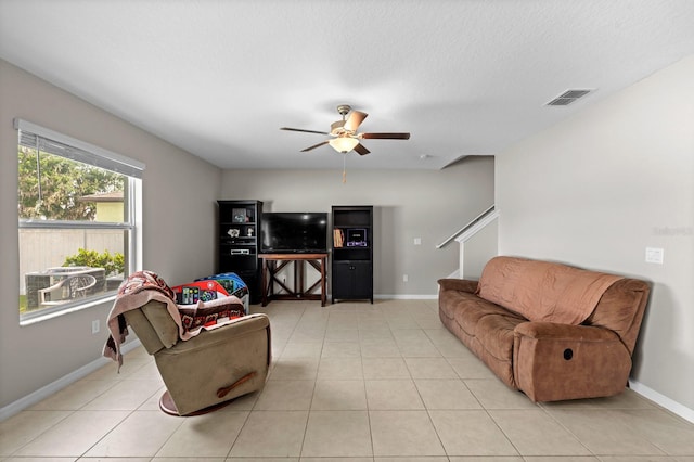 living area featuring baseboards, visible vents, light tile patterned floors, and ceiling fan