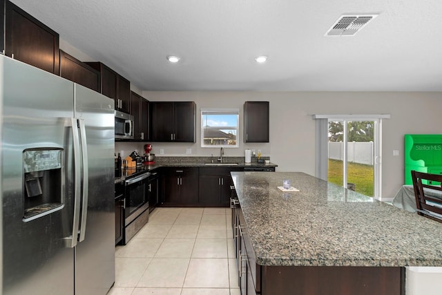 kitchen featuring dark stone counters, stainless steel appliances, visible vents, a kitchen island, and recessed lighting