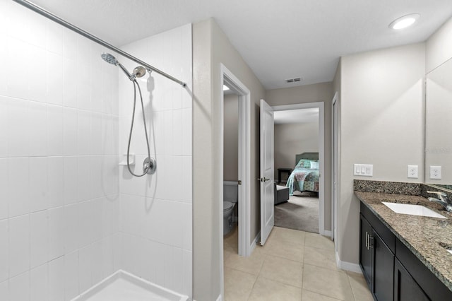 full bath featuring toilet, tiled shower, vanity, and tile patterned flooring