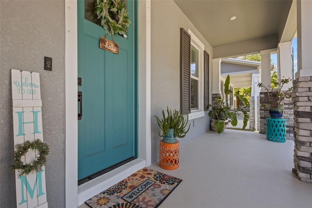 entrance to property with a porch and stucco siding