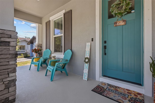 doorway to property with a porch, stucco siding, and elevator