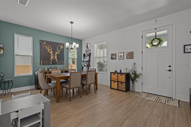 dining room featuring a chandelier, baseboards, light wood-type flooring, and visible vents