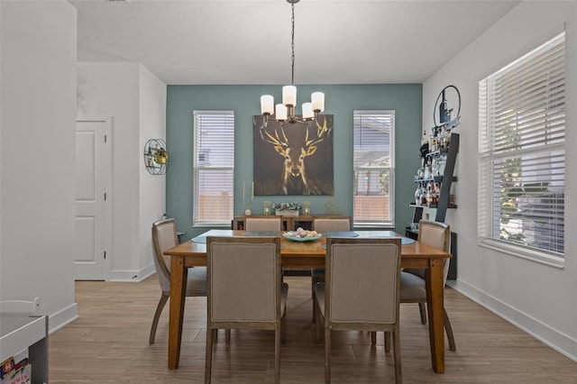 dining space with a chandelier, wood finished floors, and baseboards