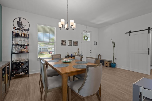 dining area with baseboards, light wood-style floors, an inviting chandelier, and a barn door
