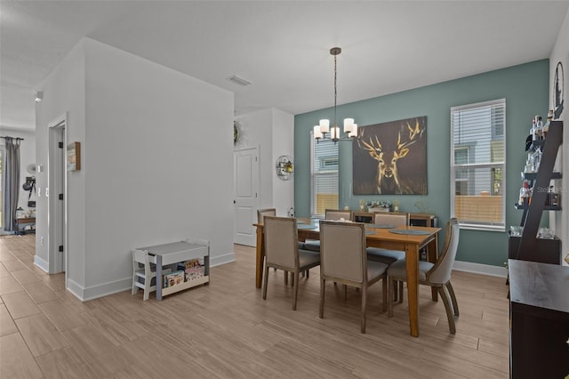 dining room featuring a chandelier, baseboards, and light wood finished floors