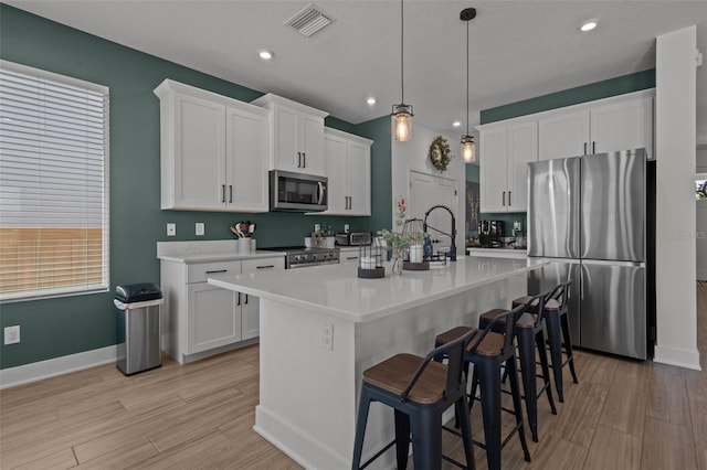 kitchen featuring stainless steel appliances, a kitchen breakfast bar, visible vents, and light wood-style floors