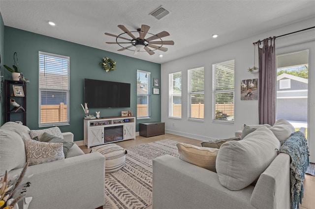 living room with a ceiling fan, recessed lighting, baseboards, visible vents, and light wood-style floors