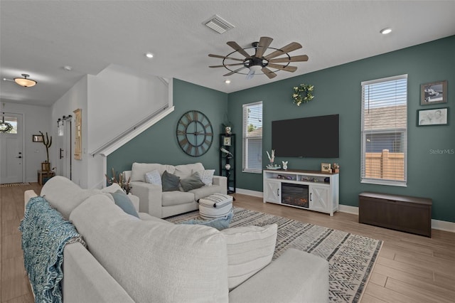 living room featuring ceiling fan, a healthy amount of sunlight, visible vents, and wood finished floors