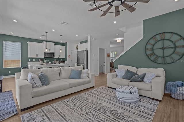 living room with ceiling fan, baseboards, light wood-type flooring, and visible vents