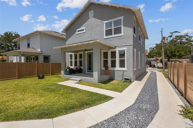 back of property featuring a ceiling fan, a yard, stucco siding, and a fenced backyard