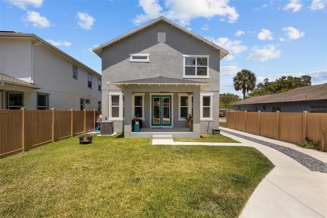 rear view of house with stucco siding, french doors, a lawn, and a fenced backyard