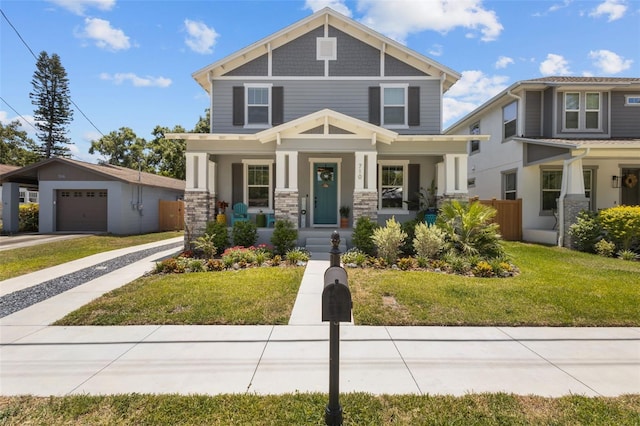 craftsman inspired home featuring covered porch, stone siding, concrete driveway, a garage, and a front lawn