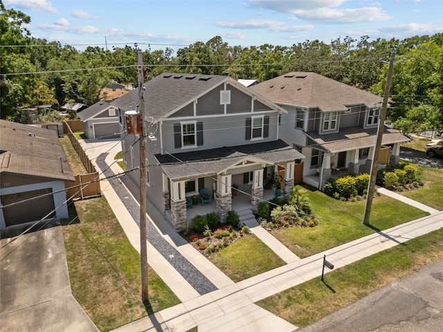 craftsman inspired home featuring covered porch, fence, a shingled roof, a front yard, and driveway