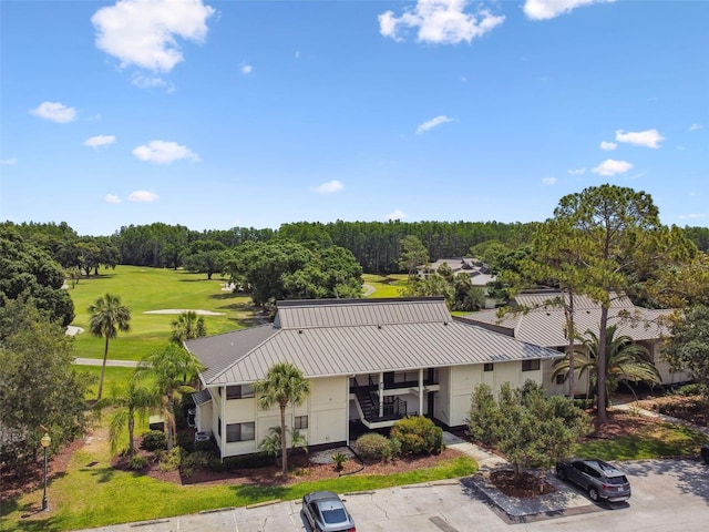 aerial view of property and surrounding area featuring a local golf course and a tree filled landscape