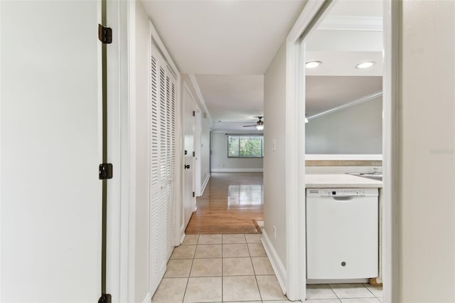 corridor with light tile patterned floors, ornamental molding, and baseboards