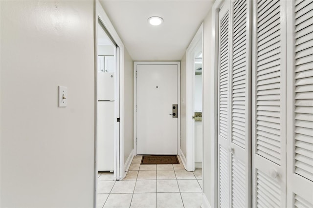hallway featuring light tile patterned flooring and baseboards