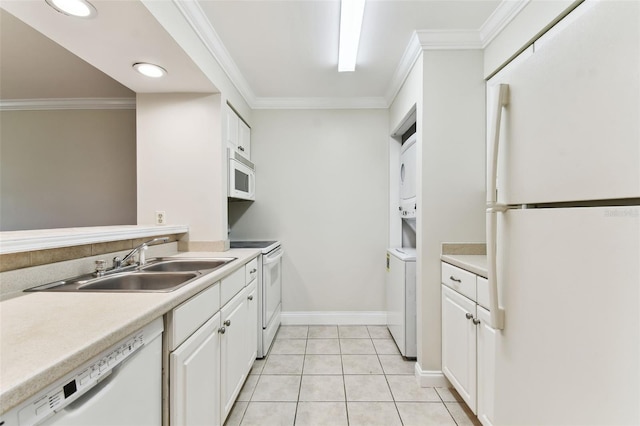 kitchen featuring white appliances, stacked washing machine and dryer, a sink, white cabinetry, and ornamental molding