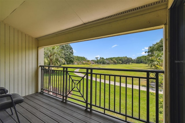wooden deck featuring golf course view, view of scattered trees, and a yard