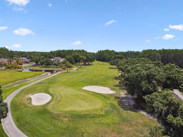 drone / aerial view of a nearby body of water, a local golf course, and a tree filled landscape
