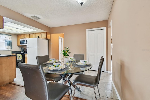 8531 Woodcrest Dr, Port Richey, FL 34668 - dining area featuring a textured ceiling, baseboards, and light tile patterned floors