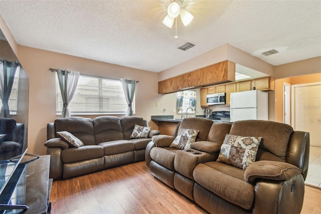 8531 Woodcrest Dr, Port Richey, FL 34668 - living area with a ceiling fan, a textured ceiling, and light wood-style floors