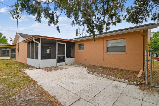 8531 Woodcrest Dr, Port Richey, FL 34668 - back of property featuring a sunroom, a patio, stucco siding, and fence
