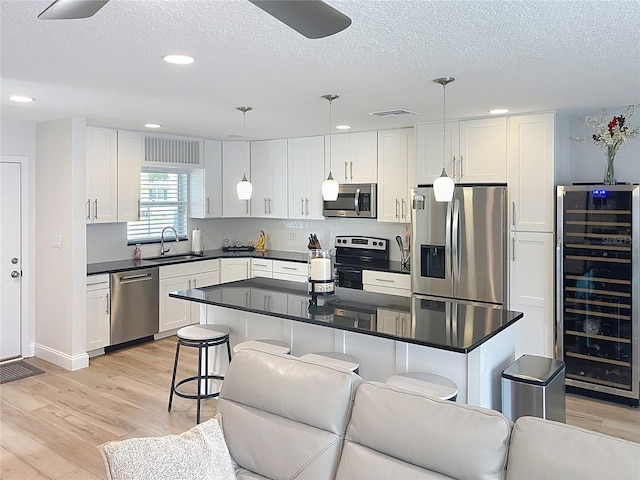 4715 W Chapin Ave, Tampa, FL 33611 - kitchen with appliances with stainless steel finishes, beverage cooler, a sink, a textured ceiling, and light wood finished floors