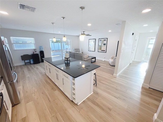 4715 W Chapin Ave, Tampa, FL 33611 - kitchen featuring dark countertops, white cabinetry, freestanding refrigerator, a center island, and open floor plan