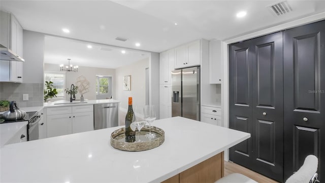 1715 N Alexander Rd, Tampa, FL 33603 - kitchen with a sink, a peninsula, backsplash, light countertops, and appliances with stainless steel finishes