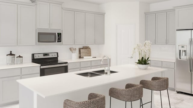 kitchen with light countertops, stainless steel appliances, a kitchen breakfast bar, and a sink