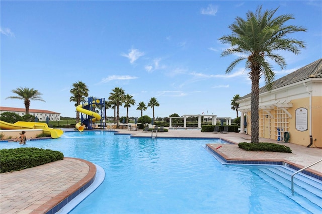 community pool featuring a water play area, a patio, a pergola, and a water slide