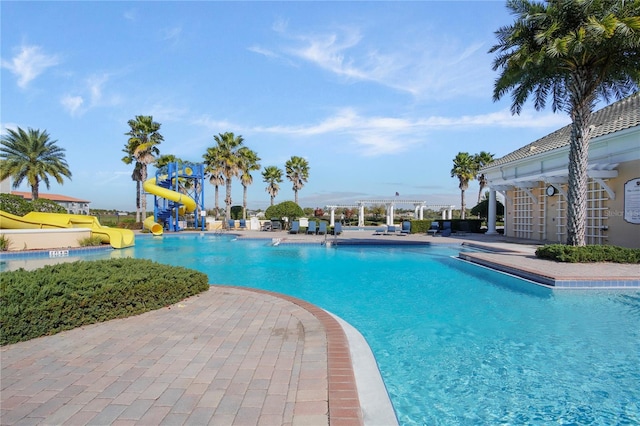 pool with a patio, a pergola, and a water slide