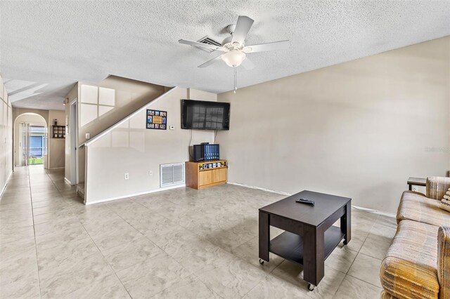 732 Kensington Lake Cir, Brandon, FL 33511 - living area with a textured ceiling, arched walkways, a ceiling fan, baseboards, and light tile patterned flooring